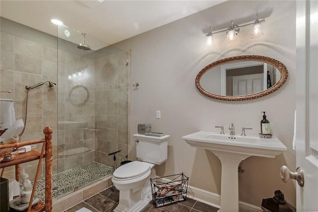 bathroom featuring tiled shower, toilet, and tile patterned flooring