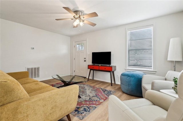 living room featuring wood-type flooring, plenty of natural light, and ceiling fan