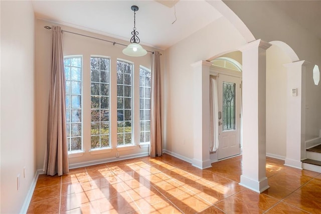 doorway to outside featuring a healthy amount of sunlight, decorative columns, and light tile patterned floors