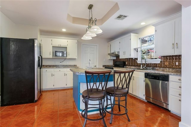 kitchen with a kitchen island, appliances with stainless steel finishes, decorative light fixtures, sink, and white cabinets