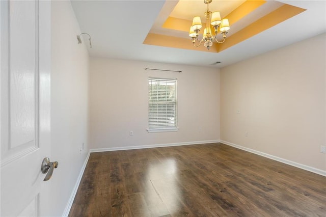 unfurnished room featuring dark hardwood / wood-style flooring, a tray ceiling, and a chandelier