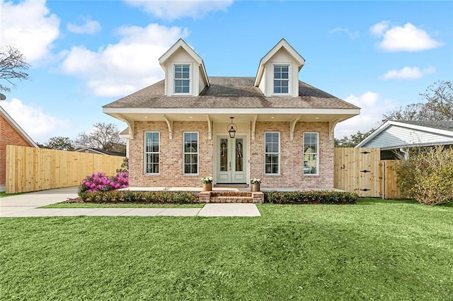 cape cod home with a front yard and covered porch