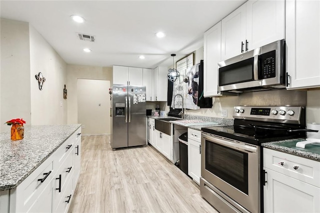 kitchen featuring light stone counters, hanging light fixtures, stainless steel appliances, and white cabinets