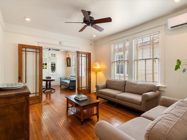 living room with a wall unit AC, wood-type flooring, a ceiling fan, and recessed lighting