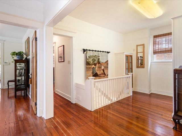 corridor with hardwood / wood-style floors, an upstairs landing, and baseboards