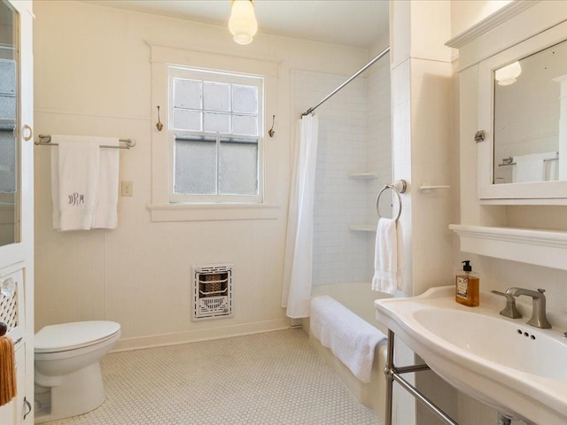 full bath with toilet, a sink, baseboards, heating unit, and shower / bath combo