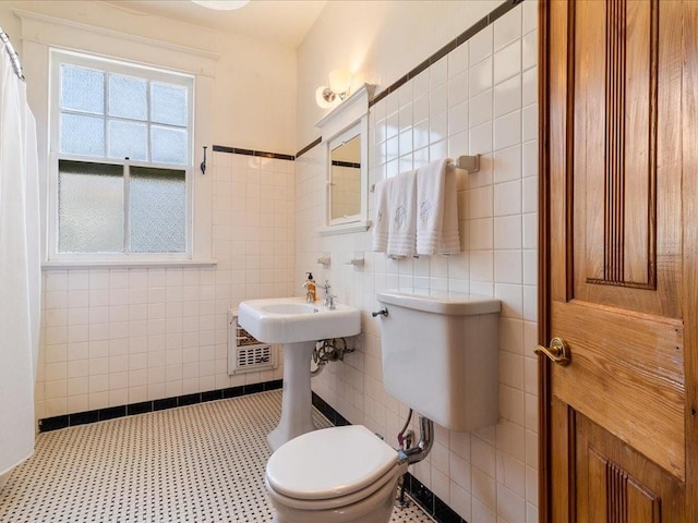 full bath featuring heating unit, toilet, and tile walls