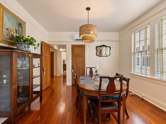 dining room featuring dark wood-style floors, a wall mounted air conditioner, a notable chandelier, and baseboards