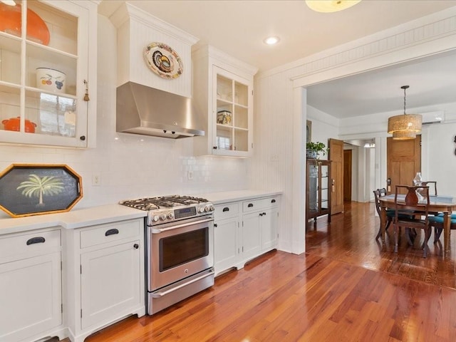 kitchen featuring stainless steel gas stove, white cabinets, glass insert cabinets, wood finished floors, and light countertops