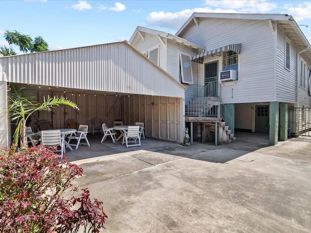 rear view of house featuring driveway, outdoor dining space, and a patio area