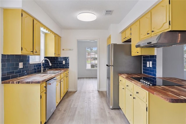 1751 Holiday Dr, New Orleans, LA 70114 - kitchen with light wood-type flooring, baseboards, under cabinet range hood, a sink, and appliances with stainless steel finishes