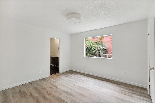 1751 Holiday Dr, New Orleans, LA 70114 - unfurnished bedroom with connected bathroom, baseboards, light wood-style floors, and a textured ceiling