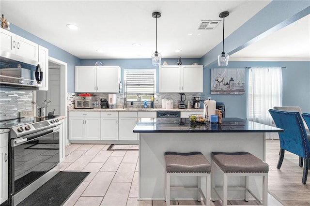 kitchen featuring stainless steel appliances, white cabinets, and decorative light fixtures