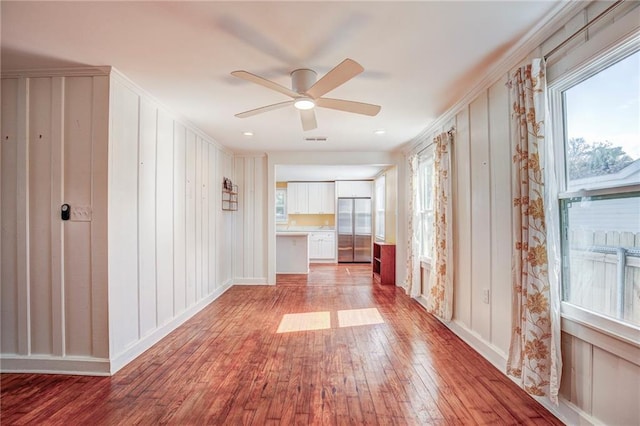 empty room featuring ceiling fan, a healthy amount of sunlight, and wood-type flooring