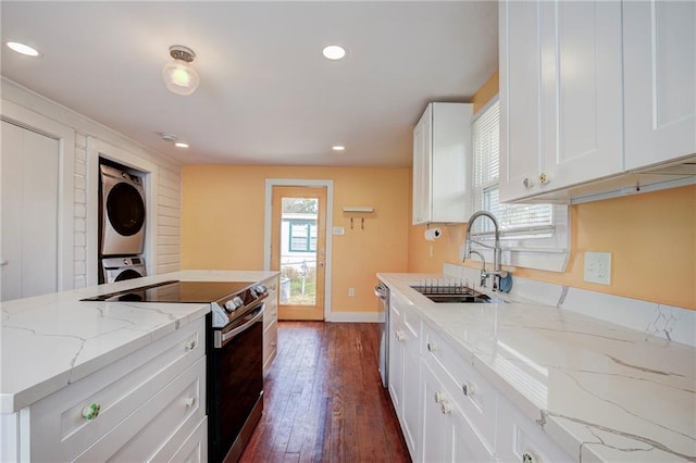 kitchen featuring appliances with stainless steel finishes, sink, white cabinets, stacked washer / drying machine, and light stone countertops