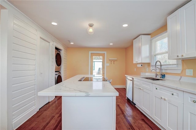 kitchen with light stone counters, stacked washing maching and dryer, a center island, and white cabinets