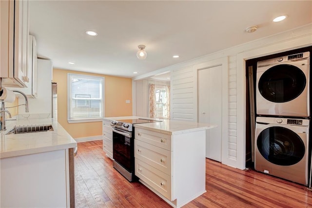 kitchen featuring a kitchen island, sink, white cabinets, stacked washer and dryer, and stainless steel electric range