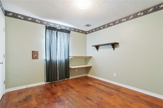 empty room featuring wood-type flooring and a textured ceiling