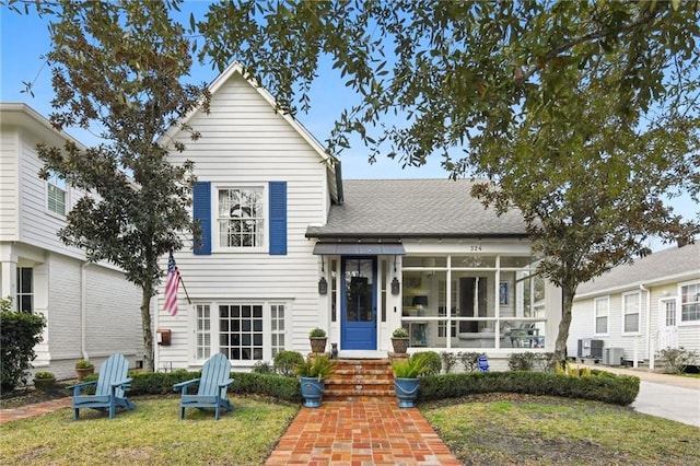 view of front of property featuring a front lawn, central AC, and a sunroom