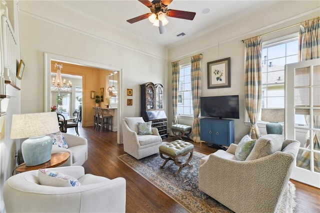 living room featuring dark hardwood / wood-style flooring, ceiling fan with notable chandelier, and a wealth of natural light