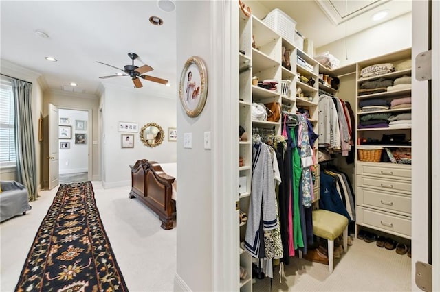 walk in closet with light carpet and ceiling fan