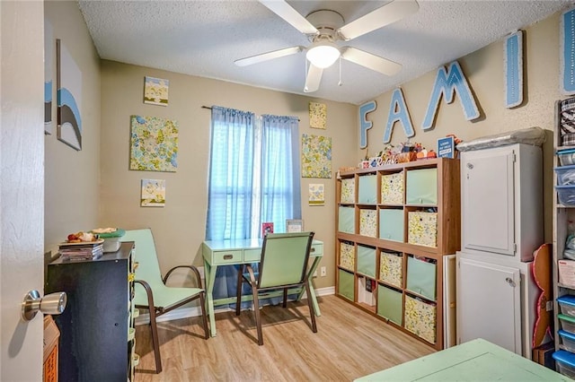 sitting room featuring ceiling fan, light hardwood / wood-style floors, and a textured ceiling