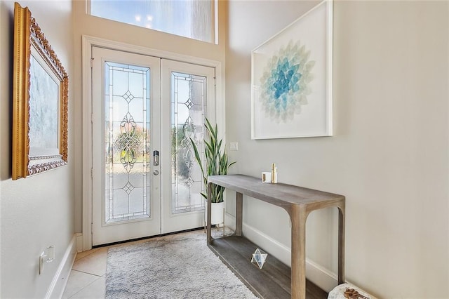 foyer with light tile patterned floors, a healthy amount of sunlight, baseboards, and french doors