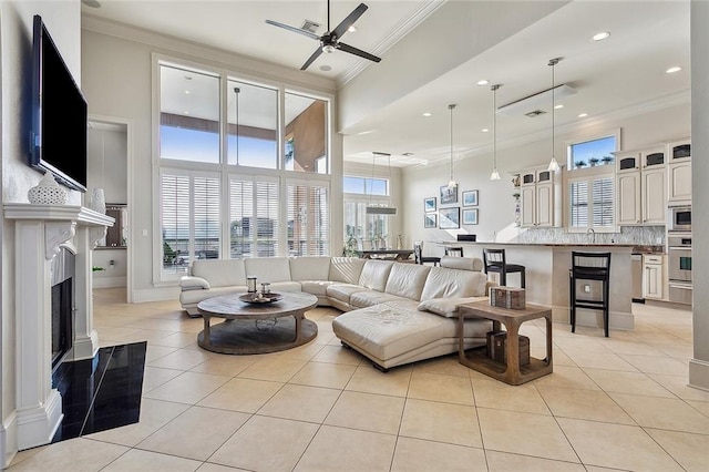 living room with light tile patterned flooring, a fireplace, a ceiling fan, and ornamental molding