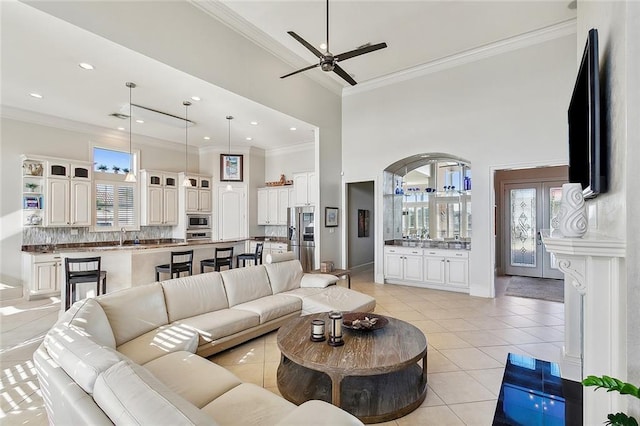 living area featuring light tile patterned flooring, plenty of natural light, ceiling fan, and ornamental molding