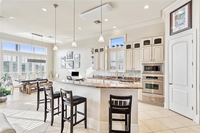 kitchen featuring visible vents, a breakfast bar, decorative backsplash, appliances with stainless steel finishes, and a sink