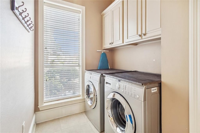 washroom featuring washing machine and clothes dryer, cabinet space, and light tile patterned flooring