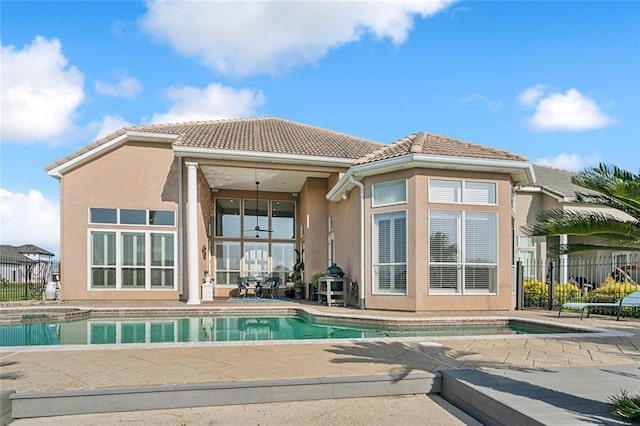 back of property featuring stucco siding, a tile roof, a patio, and fence