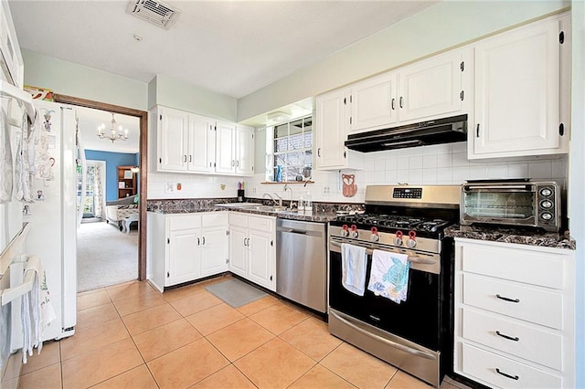 kitchen featuring tasteful backsplash, stainless steel appliances, dark stone counters, and white cabinets