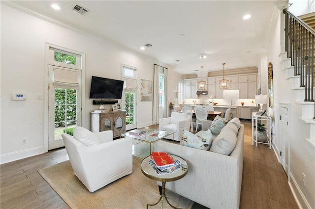 living room with hardwood / wood-style flooring, ornamental molding, and a healthy amount of sunlight