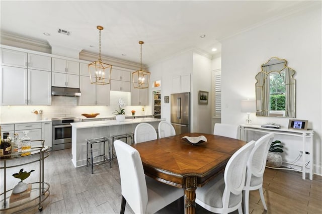 dining space featuring an inviting chandelier, ornamental molding, and wood-type flooring