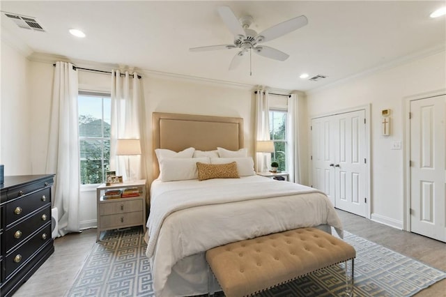 bedroom featuring crown molding, ceiling fan, multiple closets, and hardwood / wood-style floors