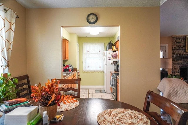 dining area with light tile patterned flooring and a brick fireplace