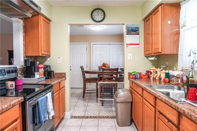 kitchen with light stone counters, sink, light tile patterned floors, and electric range