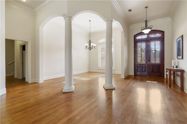 foyer entrance featuring ornate columns, ornamental molding, and hardwood / wood-style floors