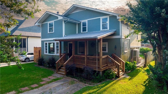 view of front of property with metal roof, covered porch, and a front lawn