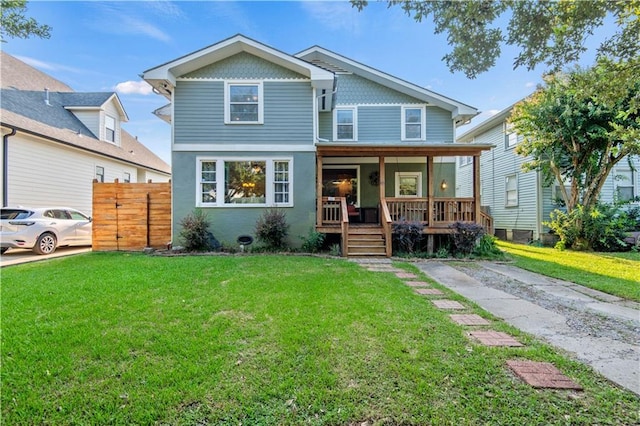 view of front of property featuring a porch, fence, and a front lawn