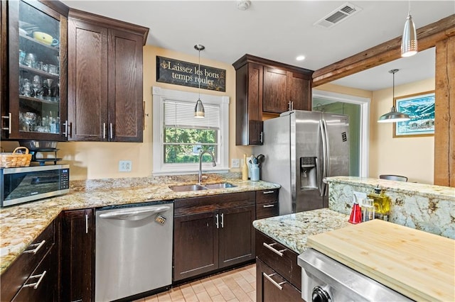 kitchen featuring visible vents, dark brown cabinetry, pendant lighting, appliances with stainless steel finishes, and a sink