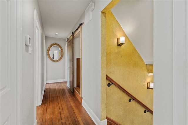 hall featuring baseboards, a barn door, and dark wood-style flooring