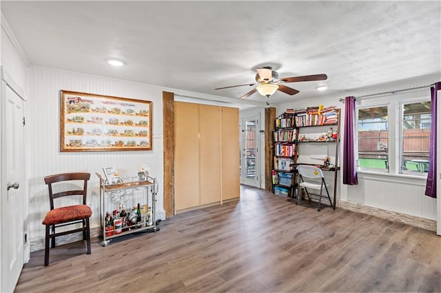 living area with crown molding, ceiling fan, and wood finished floors