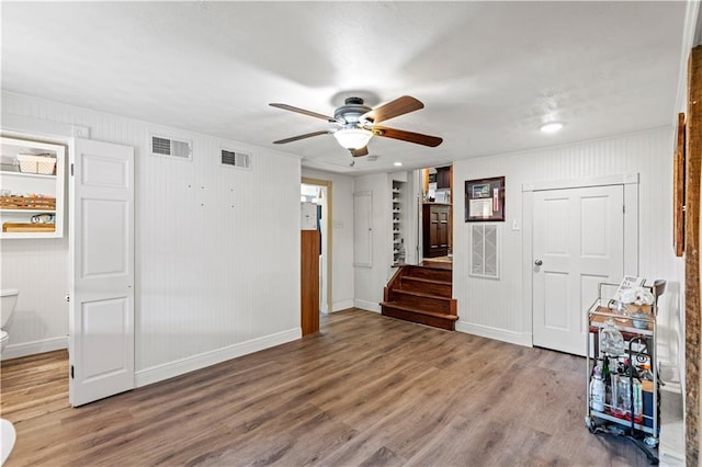 spare room with visible vents, stairs, baseboards, and wood finished floors