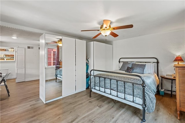 bedroom featuring visible vents, baseboards, ceiling fan, and wood finished floors