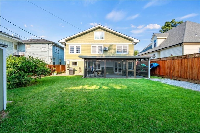 rear view of property featuring a patio area, a lawn, a fenced backyard, and a sunroom