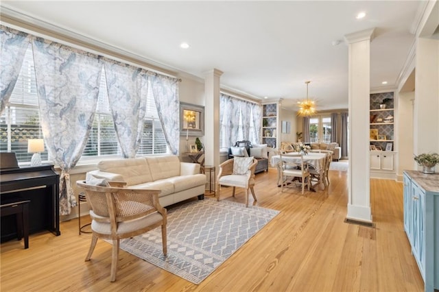 living room featuring crown molding, light wood-type flooring, and ornate columns