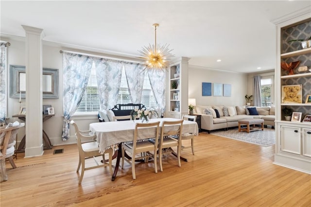 dining room featuring a notable chandelier, ornamental molding, and light wood-type flooring