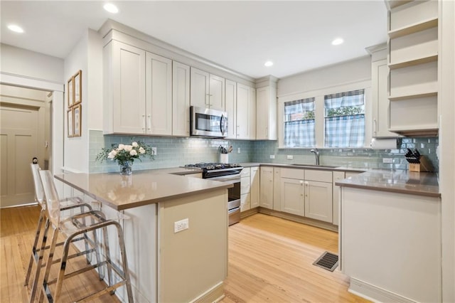 kitchen with white cabinetry, appliances with stainless steel finishes, sink, and kitchen peninsula